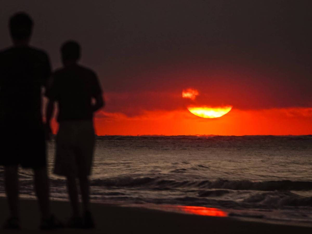 Zwei Männer am Strand bei Sonnenuntergang.