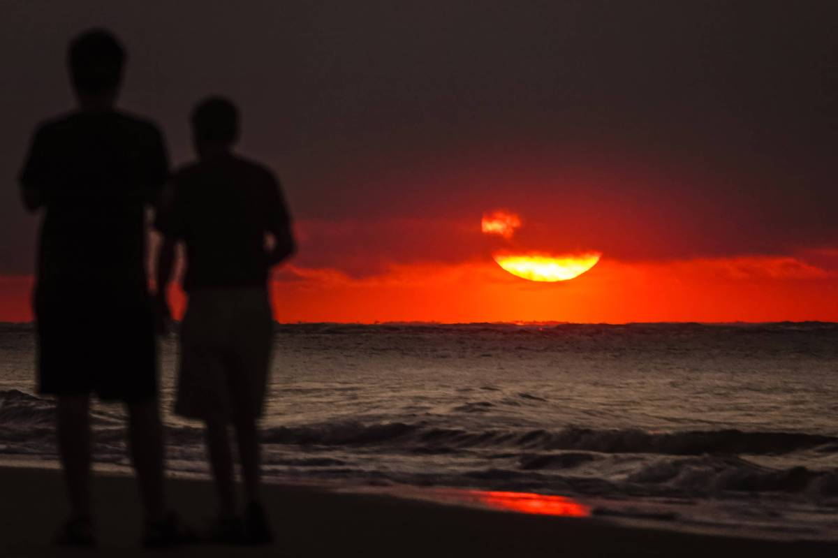 Zwei Männer am Strand bei Sonnenuntergang.