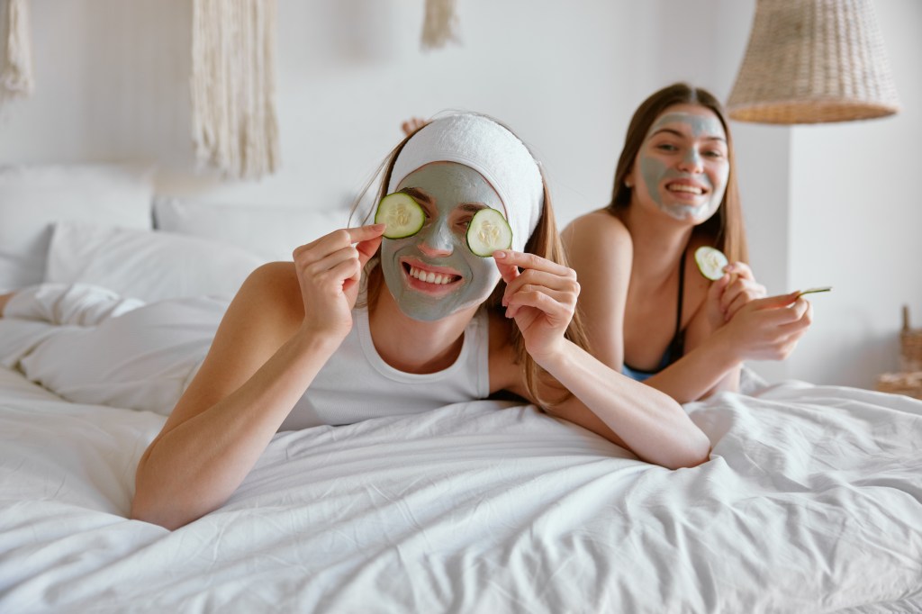 Zwei Mädchen mit Gesichtsmasken auf einem Bett.