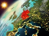 Ein Blick aus dem Orbit auf die Erde hinter der die Sonne aufsteigt. Deutschland ist mit roter Farbe markiert.