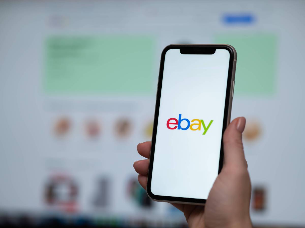Handy mit Ebay Logo vor Ebay Website