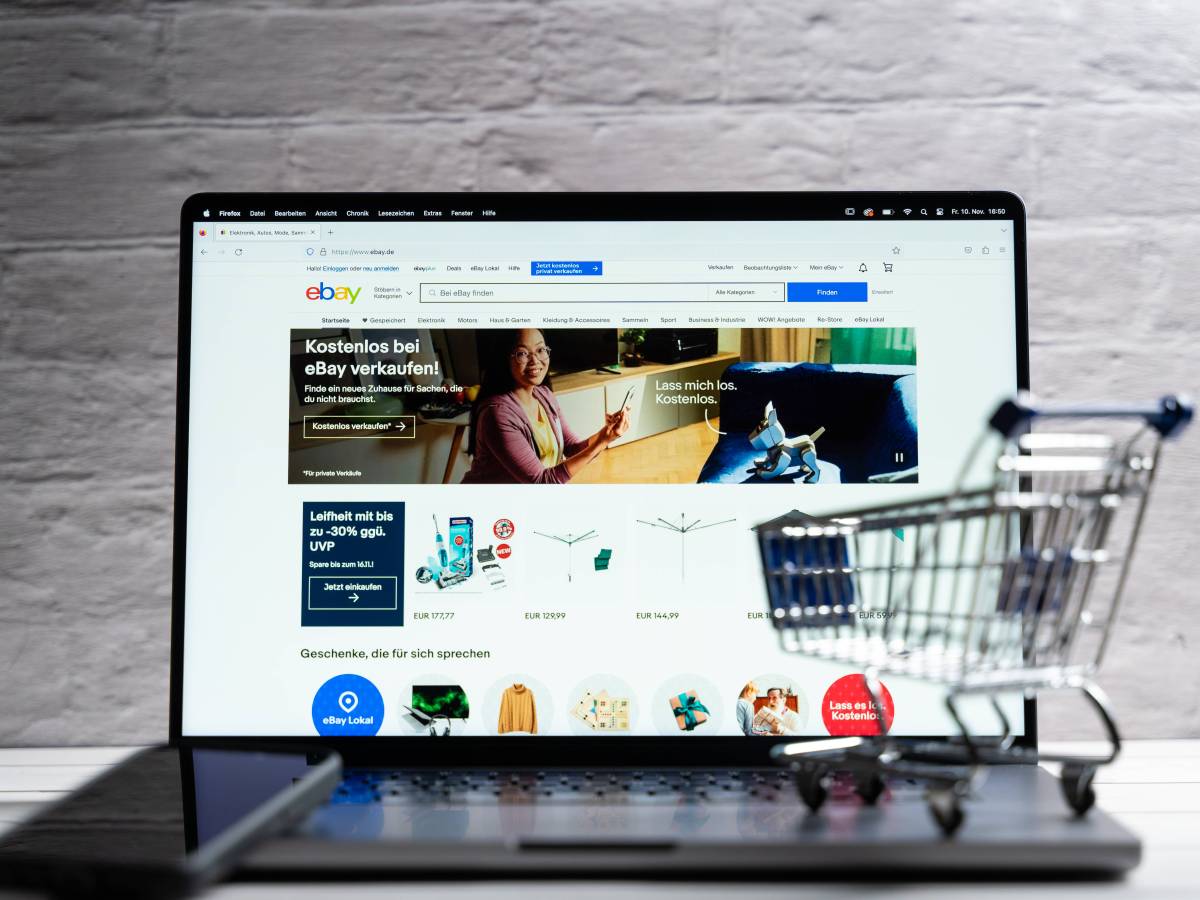 Laptop mit Ebay Seite und kleinem Einkaufswagen auf der Tastatur