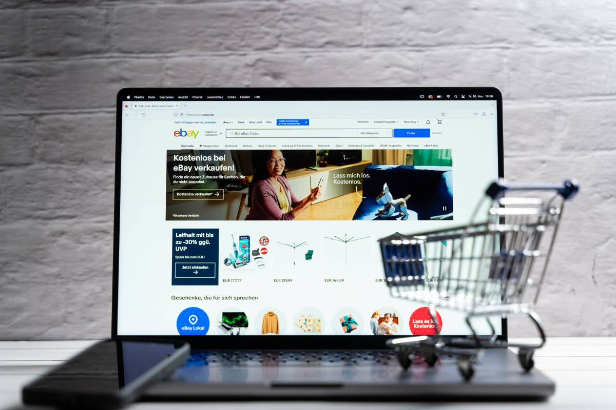 Laptop mit Ebay Seite und kleinem Einkaufswagen auf der Tastatur